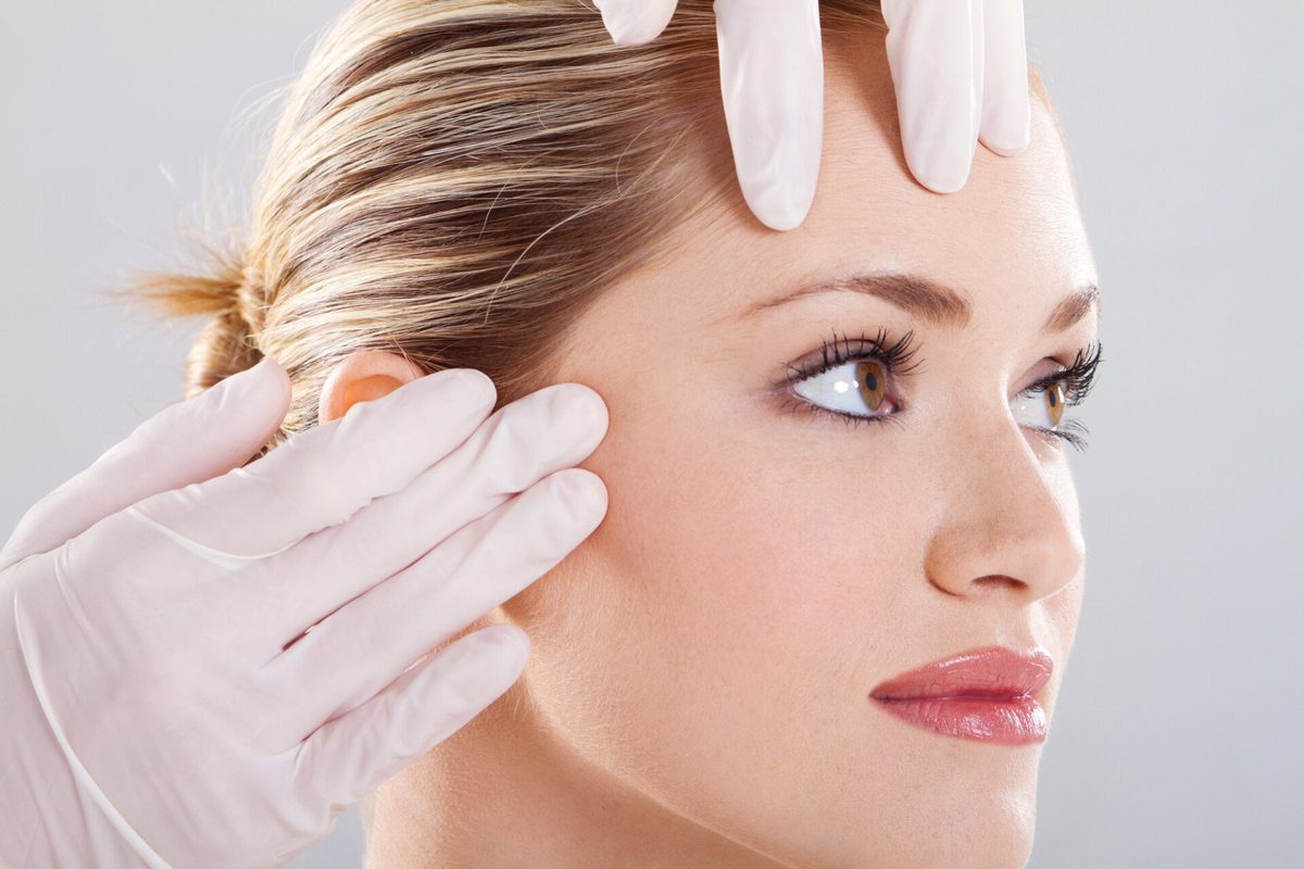 Gloved hands applying treatment to a client's face