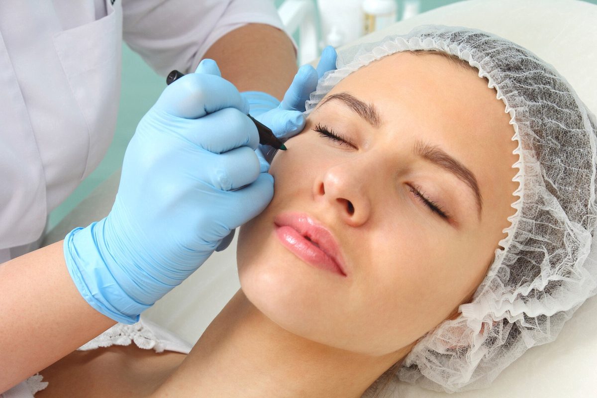 Practitioner using a microneedling pen on a client's forehead