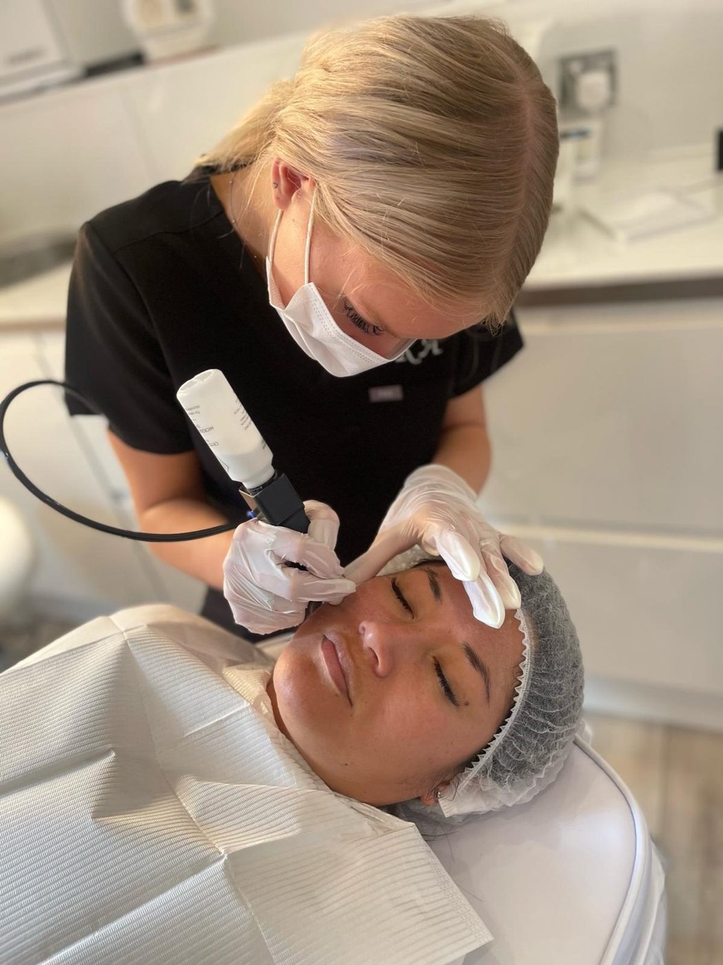 A practitioner in mask and gloves treating a client's skin in the clinic
